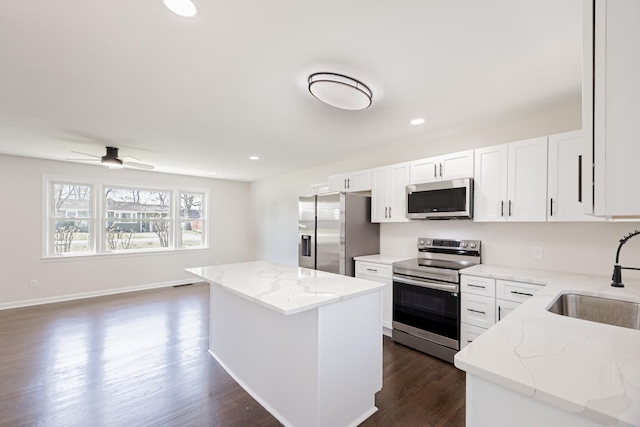 kitchen with light stone countertops, dark wood-type flooring, a center island, a sink, and stainless steel appliances