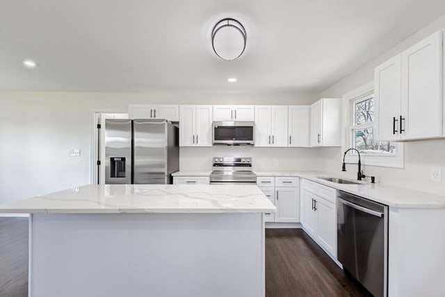 kitchen featuring a kitchen island, white cabinets, dark wood-type flooring, stainless steel appliances, and a sink