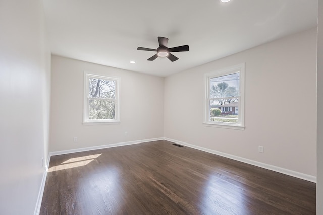 spare room featuring visible vents, baseboards, a ceiling fan, and dark wood finished floors