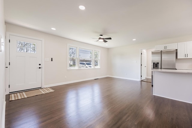 unfurnished living room with dark wood-type flooring, baseboards, a ceiling fan, and a wealth of natural light