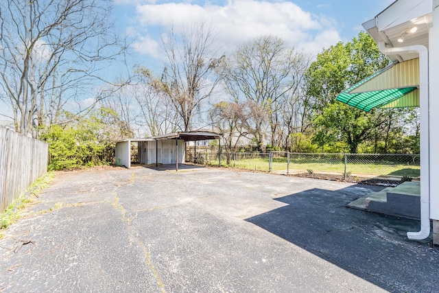 view of patio / terrace featuring an outbuilding, driveway, fence, and a gate