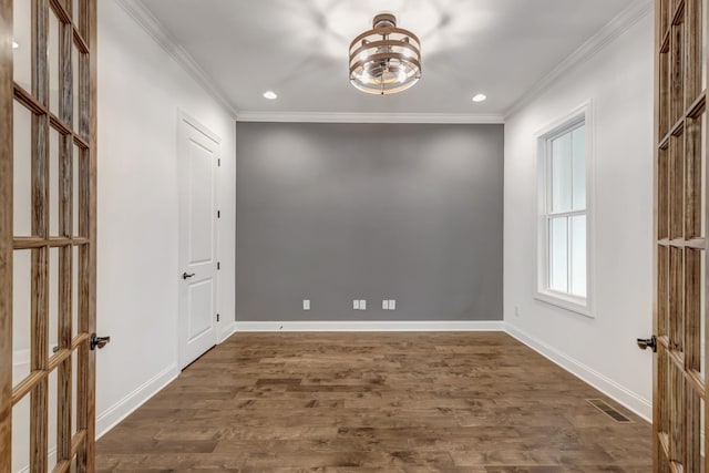 unfurnished room featuring baseboards, visible vents, crown molding, and dark wood finished floors