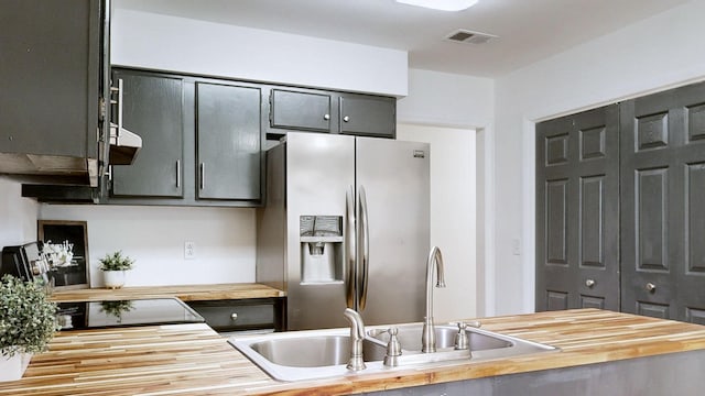 kitchen with wooden counters, visible vents, and stainless steel fridge