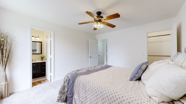 bedroom featuring baseboards, connected bathroom, ceiling fan, and light carpet