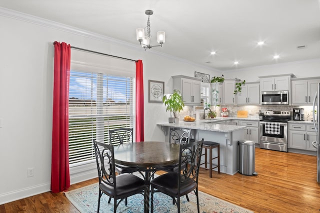 dining room featuring baseboards, crown molding, light wood-style floors, and an inviting chandelier