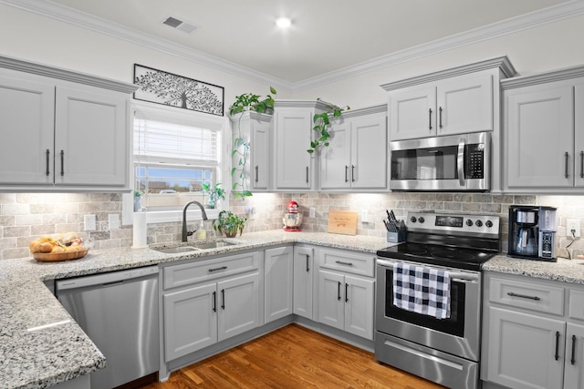 kitchen featuring visible vents, ornamental molding, a sink, and appliances with stainless steel finishes