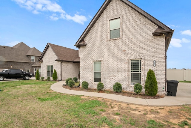 view of home's exterior featuring brick siding, fence, and a yard