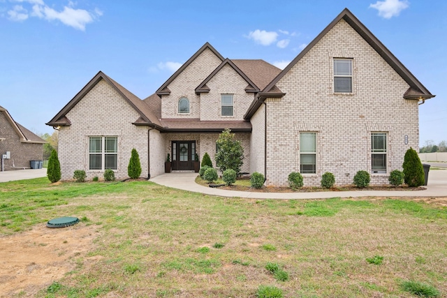 french provincial home with brick siding and a front lawn