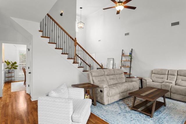 living room with visible vents, wood finished floors, stairway, and a ceiling fan