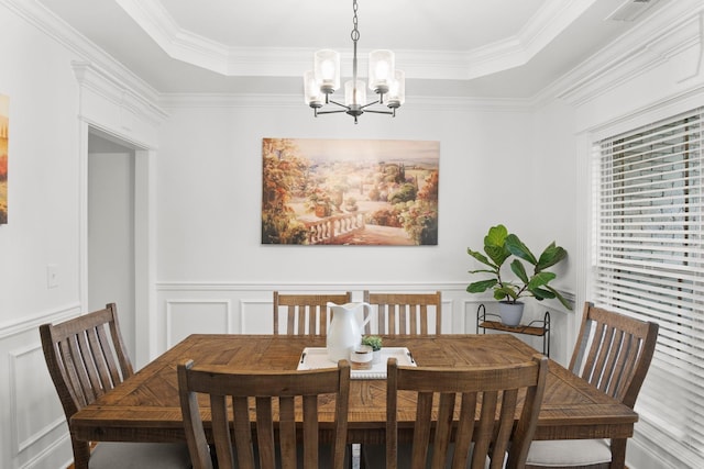 dining area featuring a tray ceiling, an inviting chandelier, a wainscoted wall, visible vents, and a decorative wall