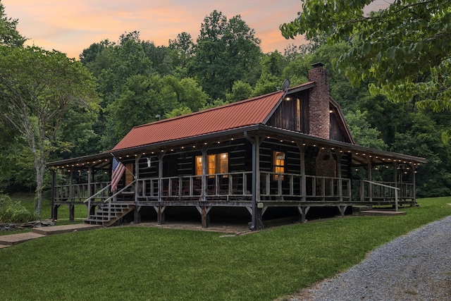 view of front of property featuring a front lawn, a gambrel roof, metal roof, and a porch