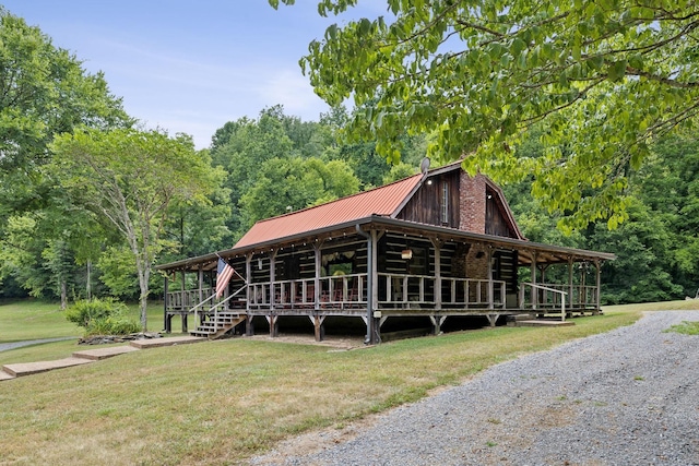 cabin featuring a gambrel roof, a forest view, a front lawn, and metal roof