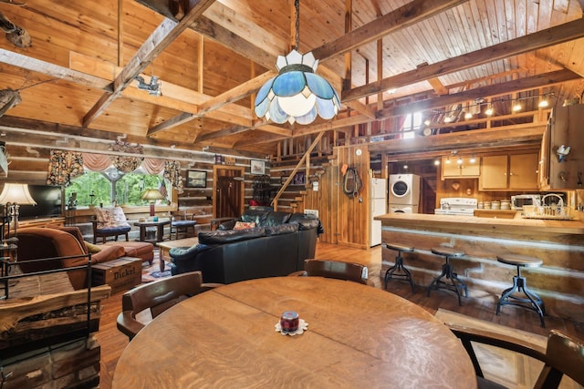 dining space with stacked washer / dryer, wood finished floors, wood walls, and wood ceiling