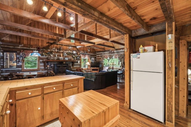 kitchen with wood finished floors, tile countertops, a wood stove, wooden ceiling, and freestanding refrigerator