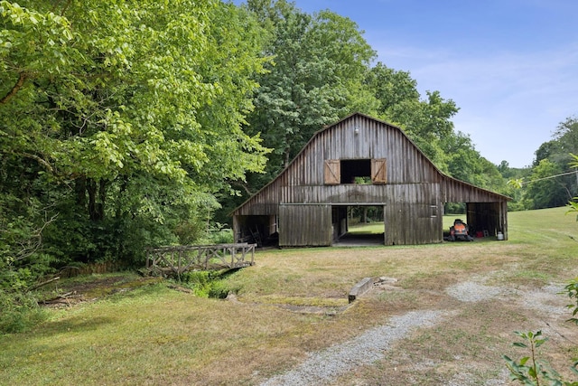 view of barn with driveway and a yard