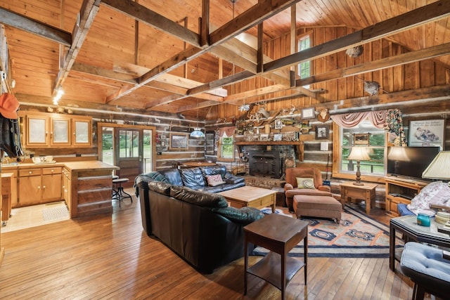 living room featuring beamed ceiling, light wood-type flooring, a wood stove, and wood ceiling