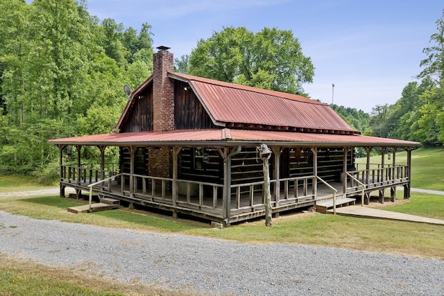 view of front of house featuring a gambrel roof, an exterior structure, a chimney, an outbuilding, and metal roof