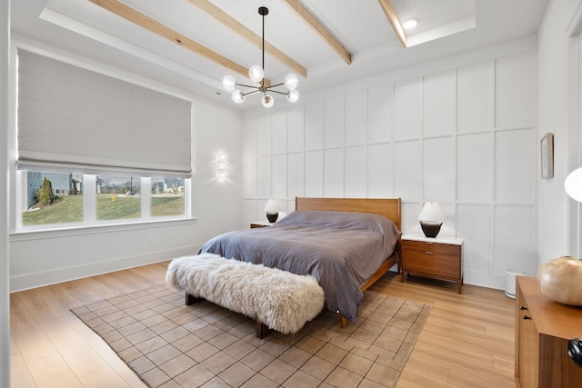 bedroom with a chandelier, a decorative wall, beam ceiling, and light wood finished floors