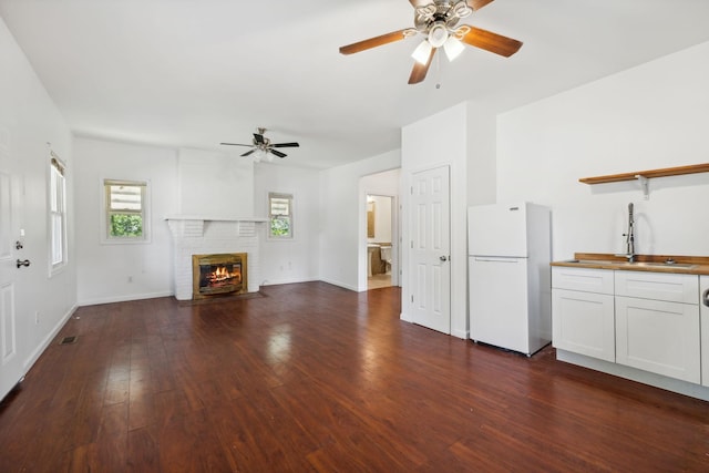 1902 Meridian St, Nashville, TN 37207 - unfurnished living room with a sink, a ceiling fan, a brick fireplace, baseboards, and dark wood-style flooring