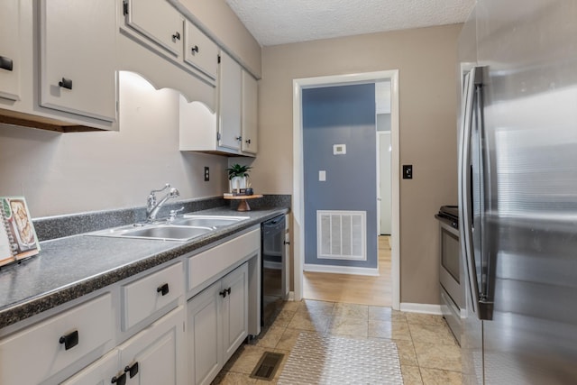 kitchen featuring a sink, visible vents, dark countertops, and freestanding refrigerator