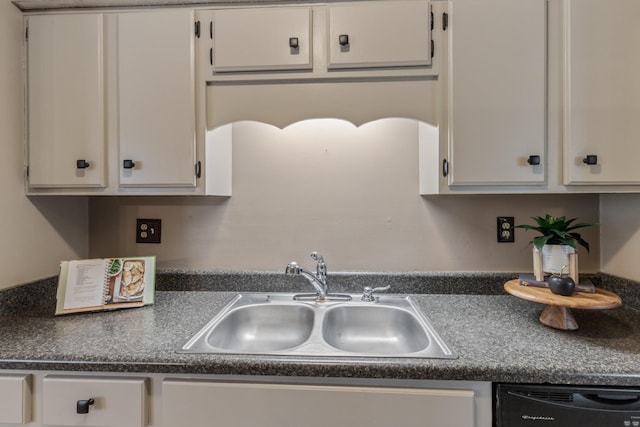 kitchen featuring dark countertops, white cabinets, a sink, and dishwasher