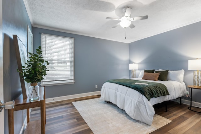 bedroom featuring baseboards, wood finished floors, ornamental molding, and a textured ceiling