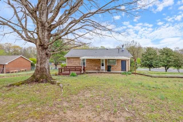 view of front facade featuring brick siding, fence, a front lawn, and a deck