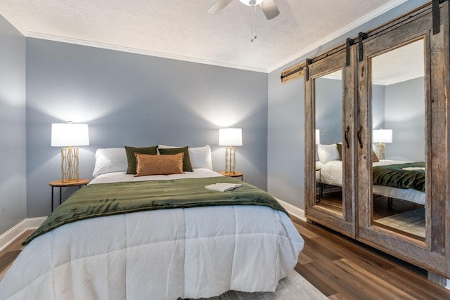 bedroom featuring crown molding, a barn door, wood finished floors, a textured ceiling, and baseboards