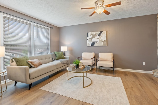 living room featuring a ceiling fan, a textured ceiling, and wood finished floors