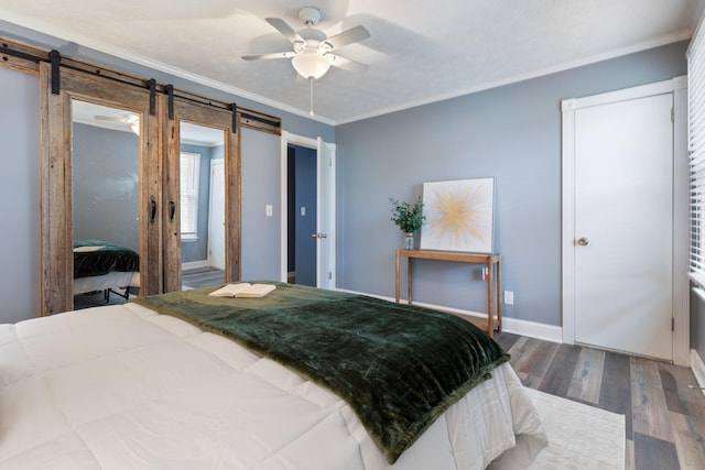 bedroom with ornamental molding, baseboards, a barn door, ceiling fan, and wood finished floors
