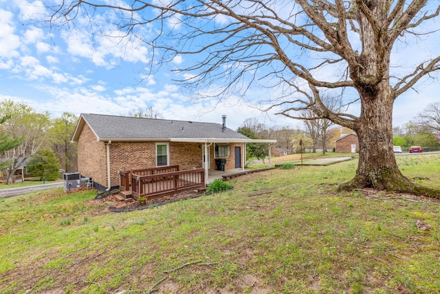 back of property featuring brick siding, central AC unit, and a yard