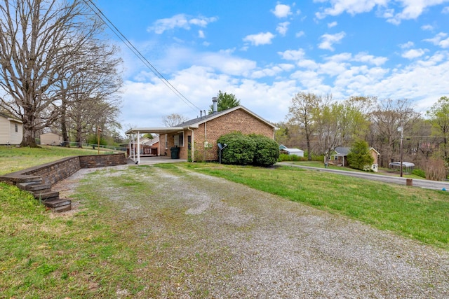 exterior space with driveway, brick siding, an attached carport, and a lawn