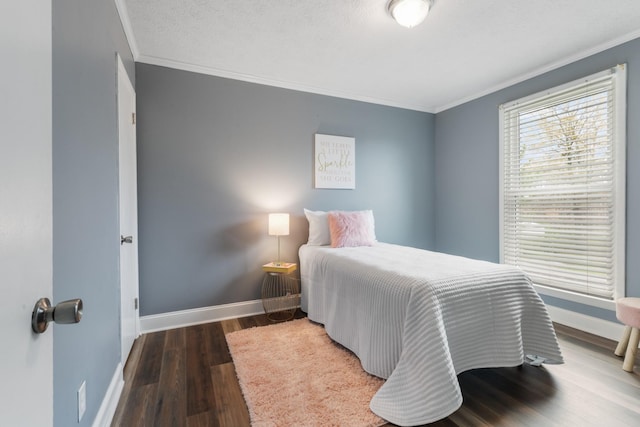 bedroom with ornamental molding, a textured ceiling, baseboards, and wood finished floors