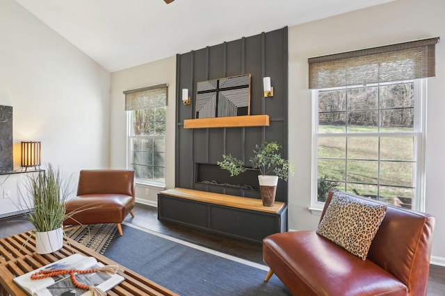 living area featuring baseboards, vaulted ceiling, and wood finished floors