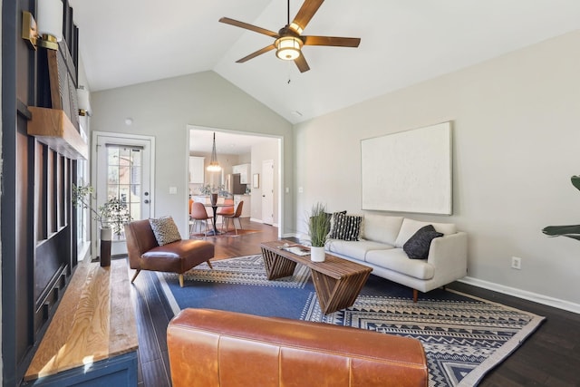 living room featuring high vaulted ceiling, ceiling fan with notable chandelier, baseboards, and wood finished floors