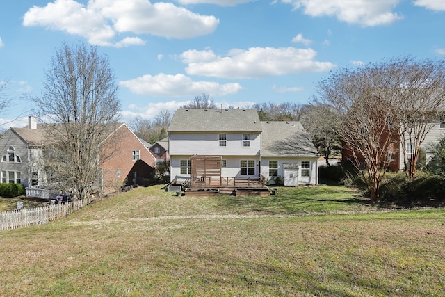 back of property featuring a lawn, a deck, and fence