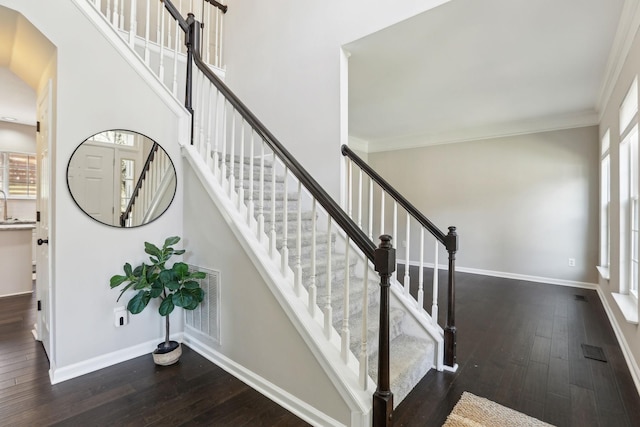 staircase with baseboards, crown molding, and wood-type flooring