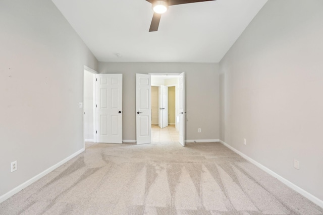 unfurnished bedroom featuring a ceiling fan, baseboards, and light colored carpet
