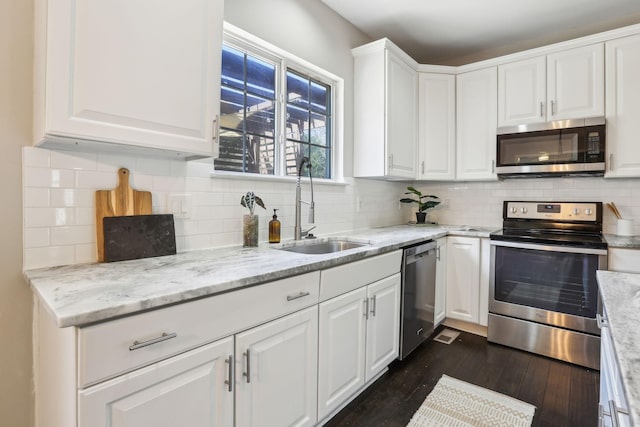 kitchen featuring white cabinetry, stainless steel appliances, backsplash, a sink, and dark wood-style floors