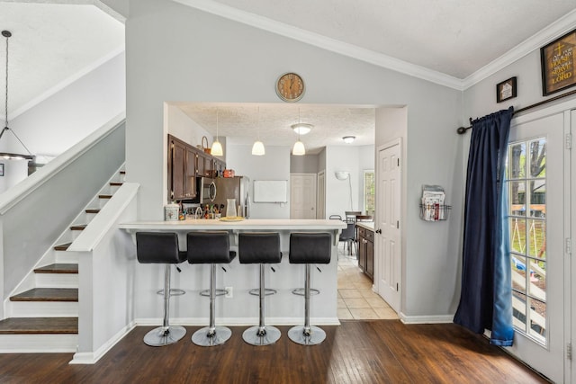 kitchen featuring a breakfast bar, a peninsula, a textured ceiling, wood-type flooring, and lofted ceiling