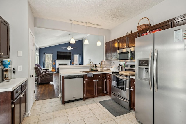 kitchen with a sink, open floor plan, ceiling fan, appliances with stainless steel finishes, and light countertops