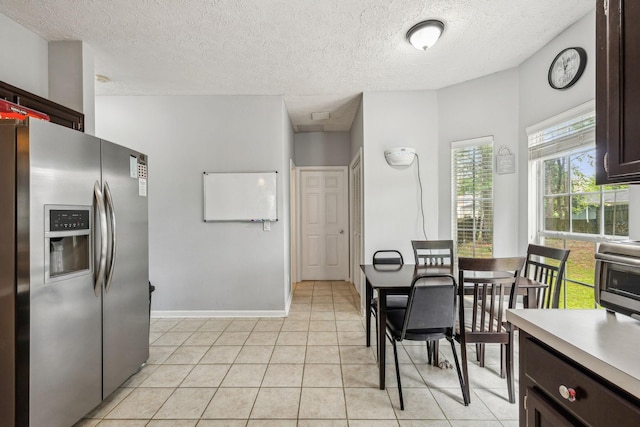 dining area with light tile patterned floors, baseboards, and a textured ceiling
