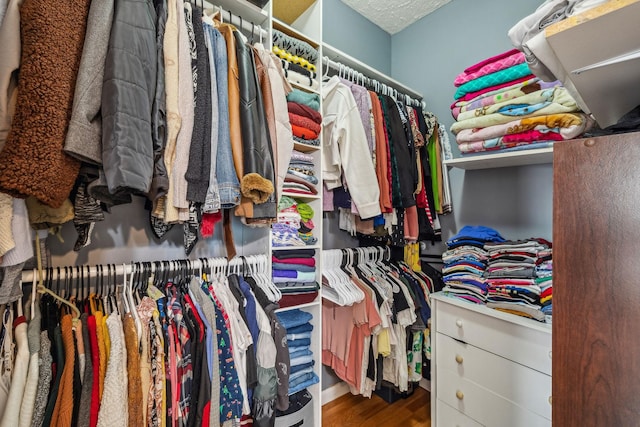 walk in closet with wood finished floors