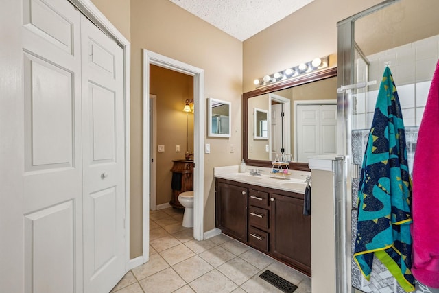 full bathroom featuring toilet, tile patterned floors, double vanity, and a sink