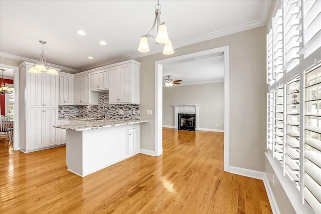 106 Irving Hills Ct, Lascassas, TN 37085 - kitchen with decorative backsplash, a peninsula, crown molding, light wood finished floors, and ceiling fan with notable chandelier