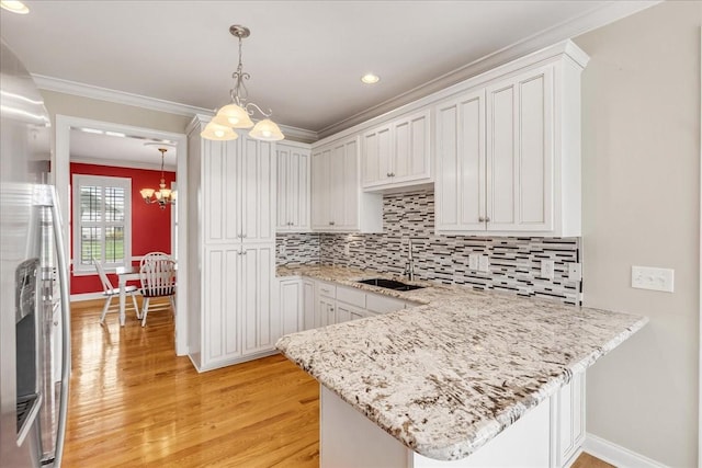 106 Irving Hills Ct, Lascassas, TN 37085 - kitchen featuring a peninsula, ornamental molding, a sink, light wood-type flooring, and an inviting chandelier