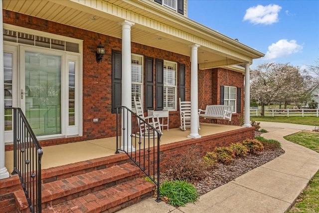 106 Irving Hills Ct, Lascassas, TN 37085 - doorway to property featuring covered porch, fence, and brick siding