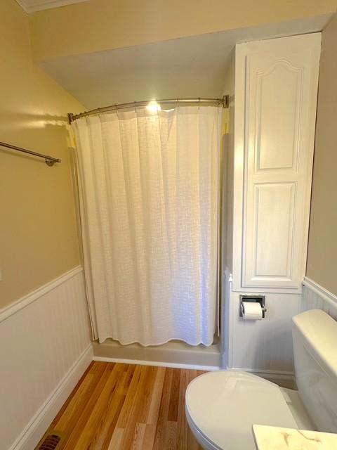 522 Norris Hancock, Big Rock, TN 37023 - bathroom featuring toilet, shower / tub combo with curtain, a wainscoted wall, and wood finished floors