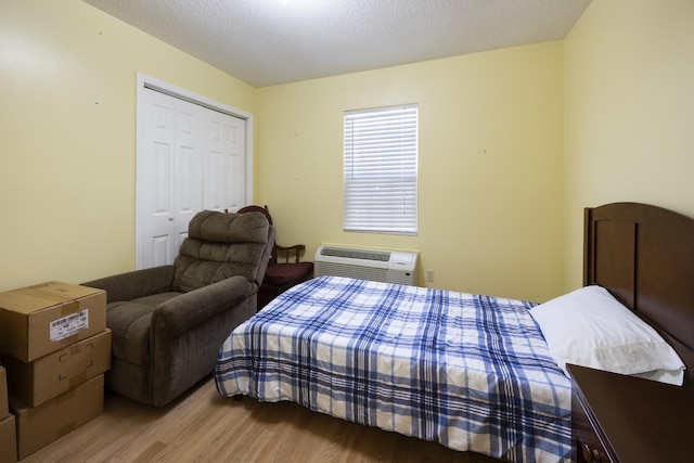 328 Cumberland St W, Cowan, TN 37318 - bedroom featuring wood finished floors, a wall unit AC, a closet, and a textured ceiling