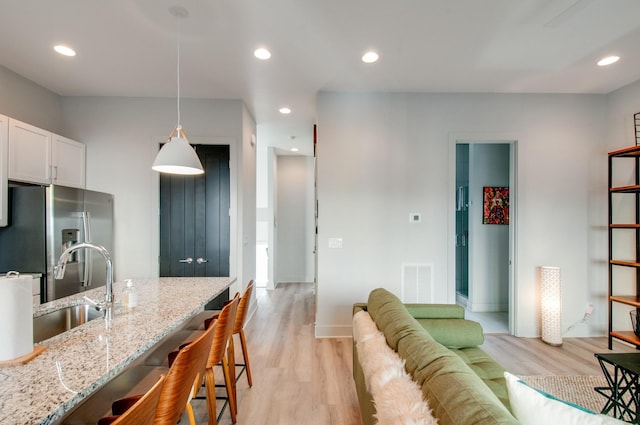 1122 Harmony Way, Nashville, TN 37207 - kitchen featuring a sink, stainless steel fridge with ice dispenser, a breakfast bar area, light wood-style flooring, and visible vents
